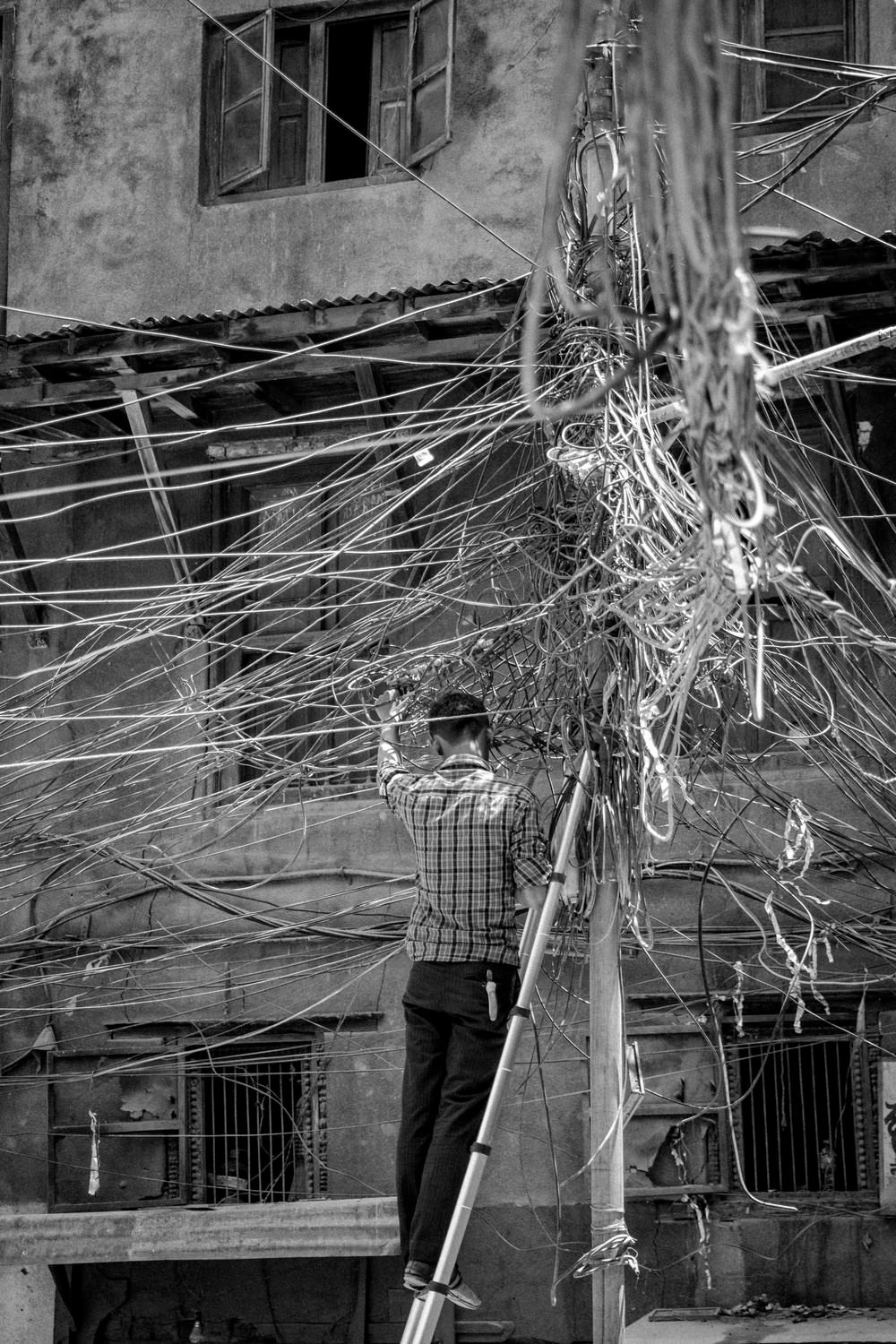A man fixes a mass of cabling in Kathmandu, Nepal